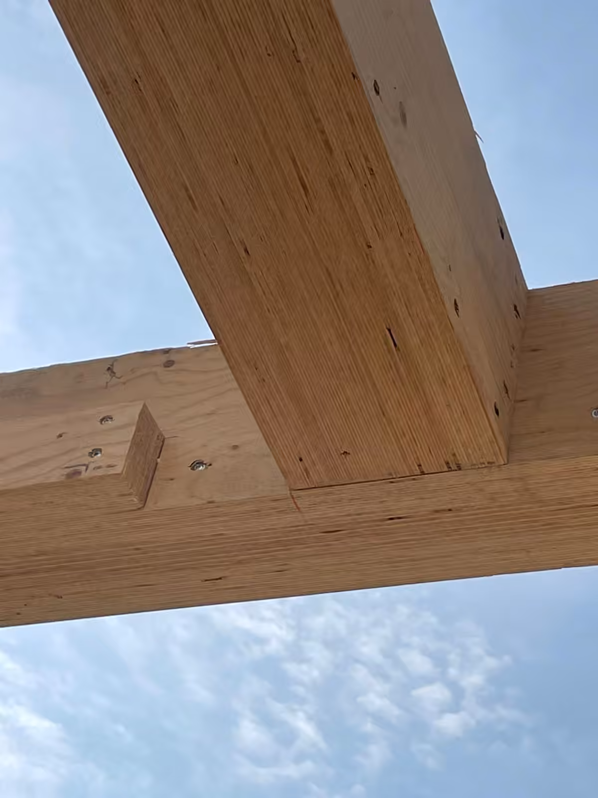 Detail van een houten draagbalk tegen een blauwe hemel