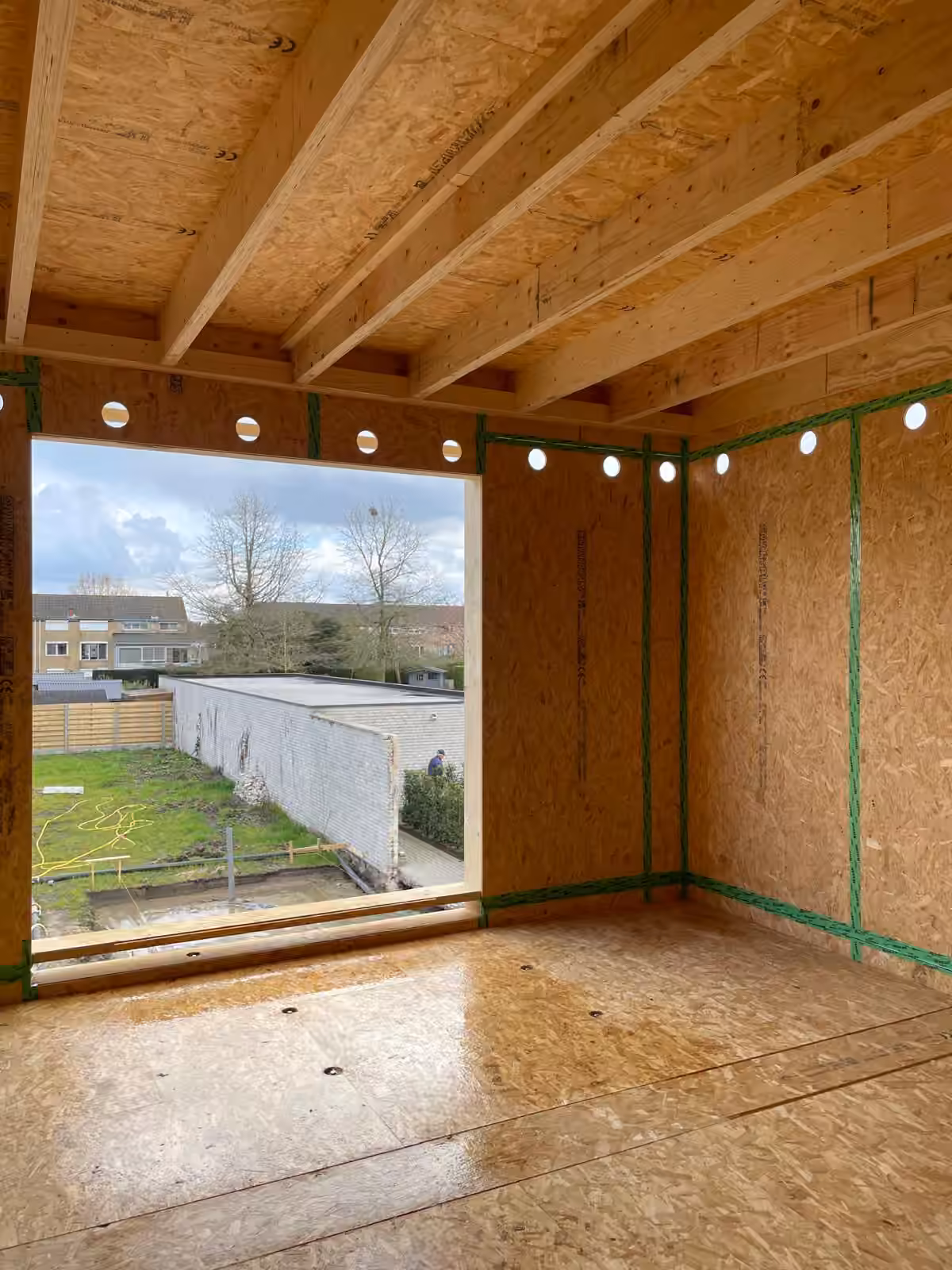 Afgewerkte leefruimte met warme houten plafondafwerking en sfeerverlichting