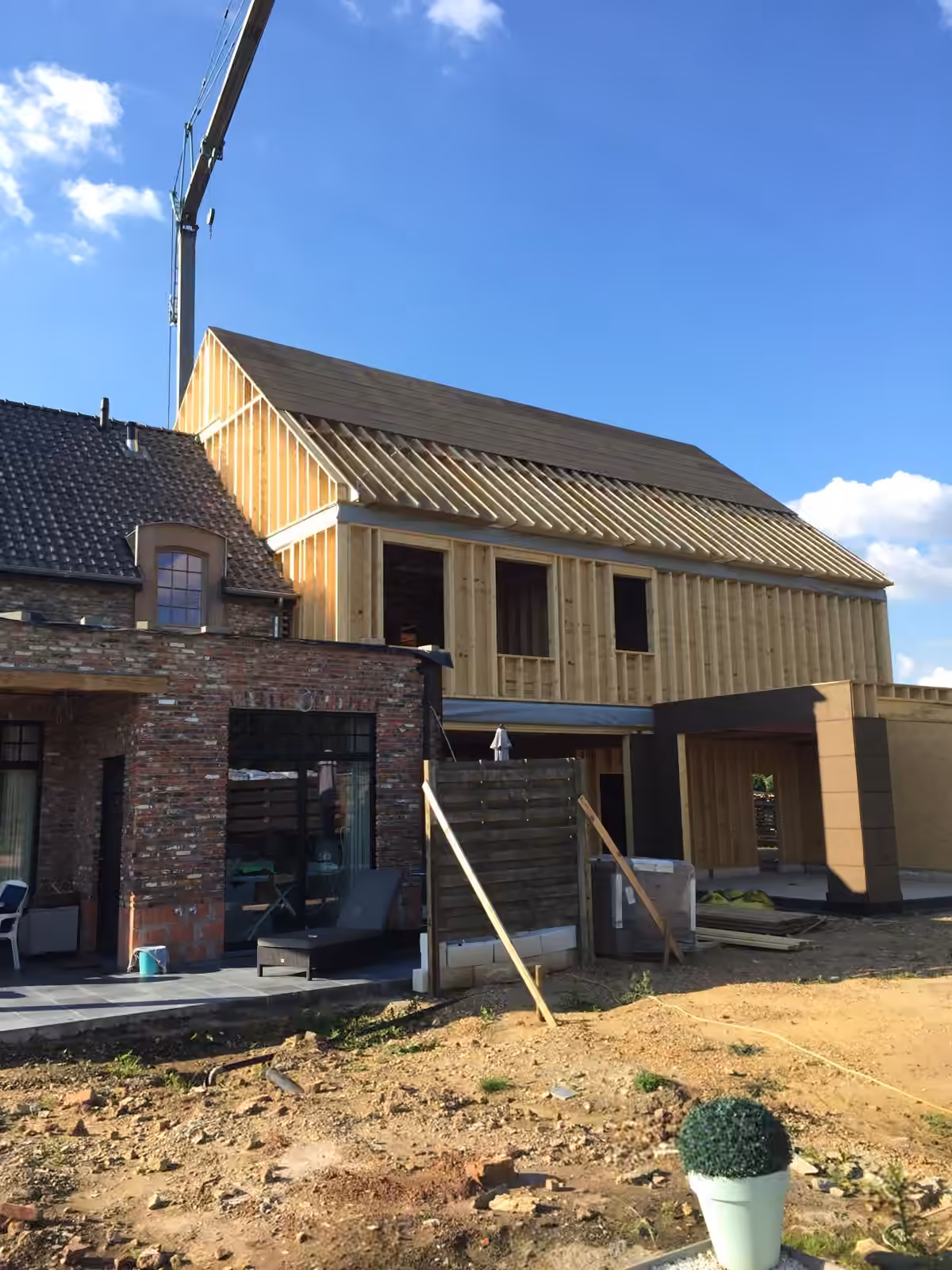 Houtskeletwoning in opbouw met aangelegde tuin op een zonnige dag