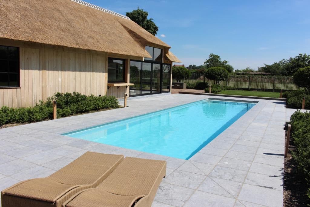PPC-zwembad naast een houten poolhouse met ligzetels
